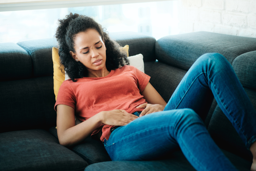 Woman With Menstrual Pain Lying On Sofa
