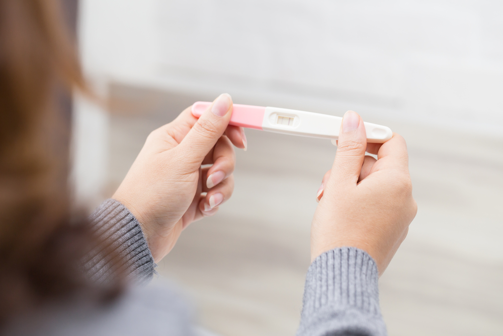 Woman holding pregnancy test.