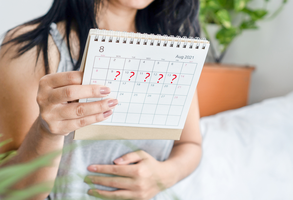 woman hand holding calendar with question mark waiting for late blood period.